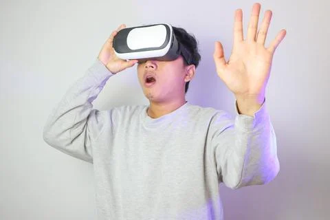Asian using VR headset smile with hand pointing to space on web banner ligh.. Stock Photos