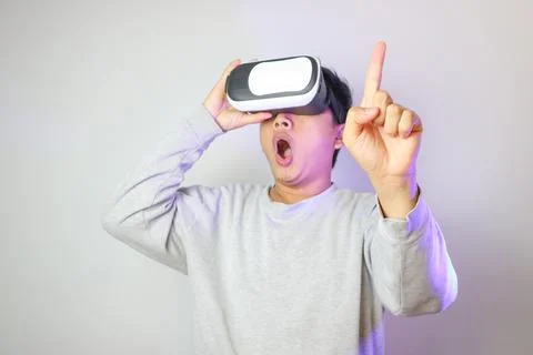 Asian using VR headset smile with hand pointing to space on web banner ligh.. Stock Photos