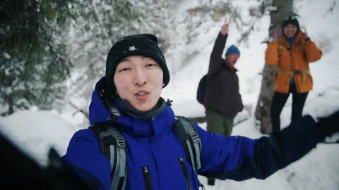 Asian vlogger talking with friends while hiking in snowy forest Stock Footage 331671131