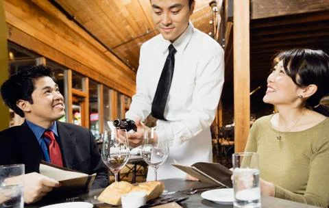 Asian waiter pouring wine for customers Stock Photos
