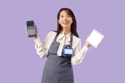 Asian waitress with blank tablet computer and payment terminal on lilac backg Stock Photos