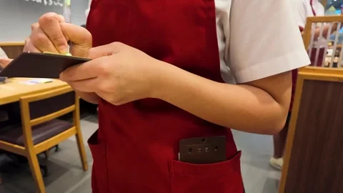 Asian Waitress in Red Apron Writing Order on Notepad in Restaurant Stock Footage 340005759