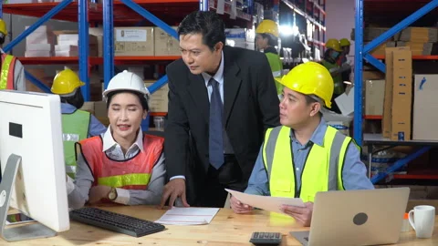 Asian warehouse manager talking to worker with computer and laptop in large w Stock Footage 141411727