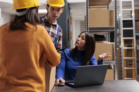 Asian warehouse workers team doing inventory tracking on laptop Stock Photos