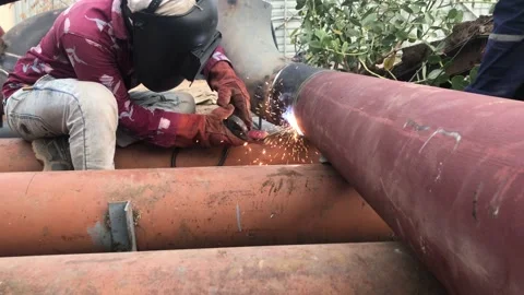 Asian welder doing down hand arc welding of mild steel pipe Stock Footage 157284153