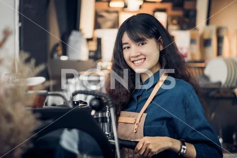 Asian woman barista making hot coffee with machine at counter bar in cafe res Stock Photos