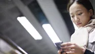 Asian Woman Checking Her Phone Whilst Using A Moving Walkway, In Slow Motion Stock Footage