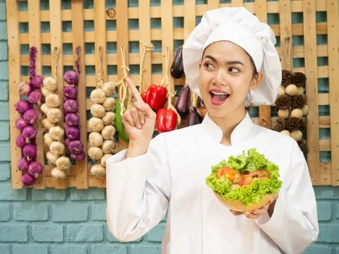 Asian woman in chef's uniform is cooking in the kitchen. Stock Photos
