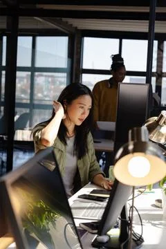 Asian woman coding on computer at modern office, focused and determined. Tech Stock Photos