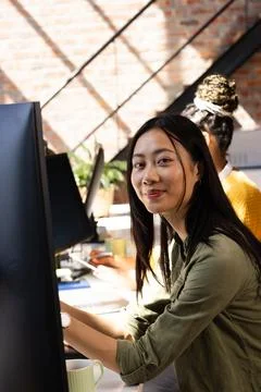Asian woman coding on computer in modern office, smiling confidently. Technol Stock Photos