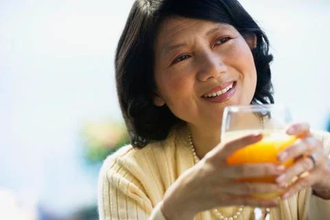 Asian woman drinking orange juice Stock Photos