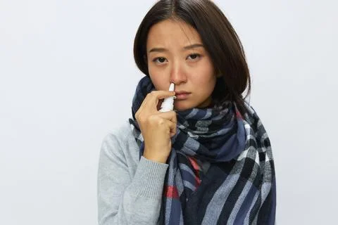 Asian woman flu cold with stuffy nose holds nasal spray and sprays nasal spray Stock Photos