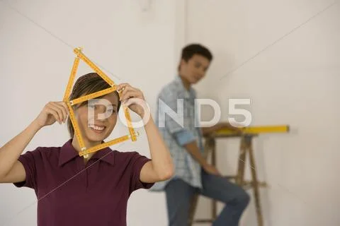 Asian woman with folding ruler shaped like house Stock-Fotos