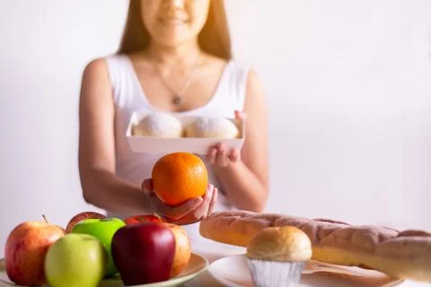 Asian woman hands holding orange and bread on white background,Healthy diet Stock Photos