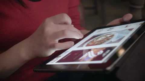 An Asian woman having a coffee in a coffee shop and browsing the web on a tablet Stock Footage 59761116