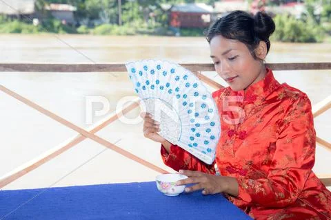 Asian Woman Holding Fan And Cup At Porch