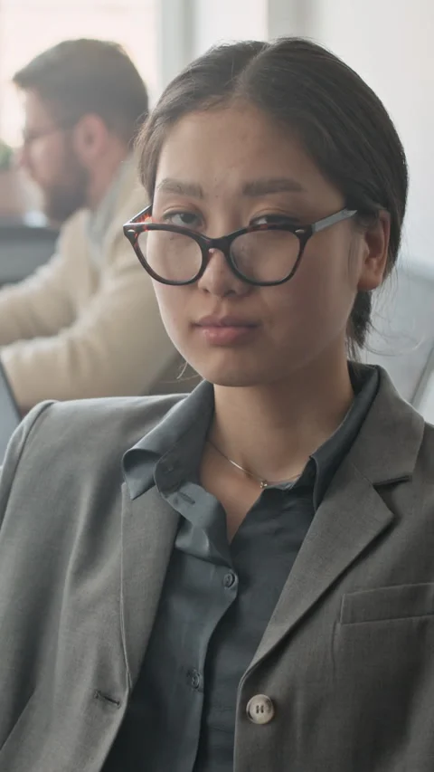Asian Woman Looking at Camera while Sitting in Computer Chair Stock Footage 333634107