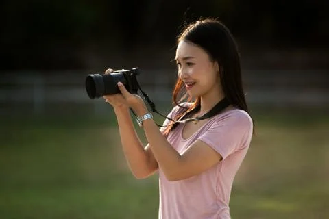 Asian woman looking through photos on camera to check quality of shots Stock Photos