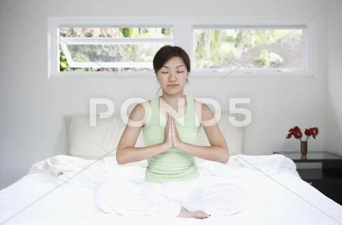 Asian woman meditating on bed Stock Photos