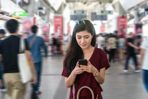 Asian woman passenger with casual suit using the smart mobile phone in the BT Stock Photos