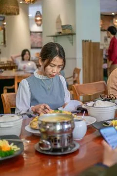 Asian woman reading a document while dining at a restaurant Foto stock