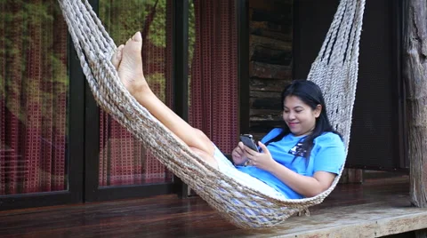 Asian woman relax on a hammock using smartphone Stock Footage 55579422
