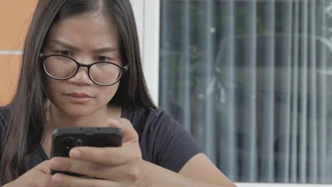 An Asian woman with serious expression while using phone. Video stock 174020637