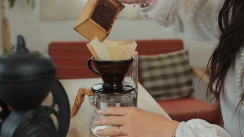 Asian woman sets ground coffee beans to the dripper. No face. 25P Stock Footage 224382053