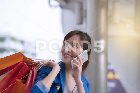 Asian woman shopping smile and holding shopping bag with cell phone, consume Stock Photos