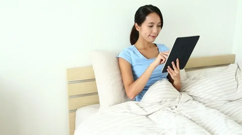 Asian Woman using digital tablet computer on bed Stock Footage 65219215
