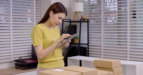 Asian woman using digital tablet to check e-commerce order, preparing parcel Stock Footage 330841156