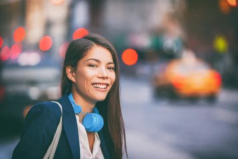 Asian woman using headphones walking on NYC New York city street work commute in Stock Photos