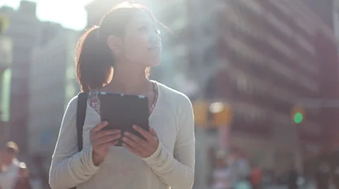 Asian woman using iPad on a city street Stock Footage
