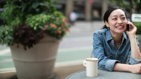 Asian woman using iPhone calling talking cellphone at outdoor cafe Video stock 27521264