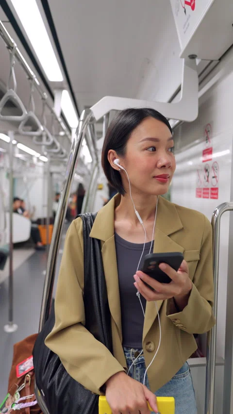 Asian woman using smartphone during morning commute on a city train Stock Footage 345959995