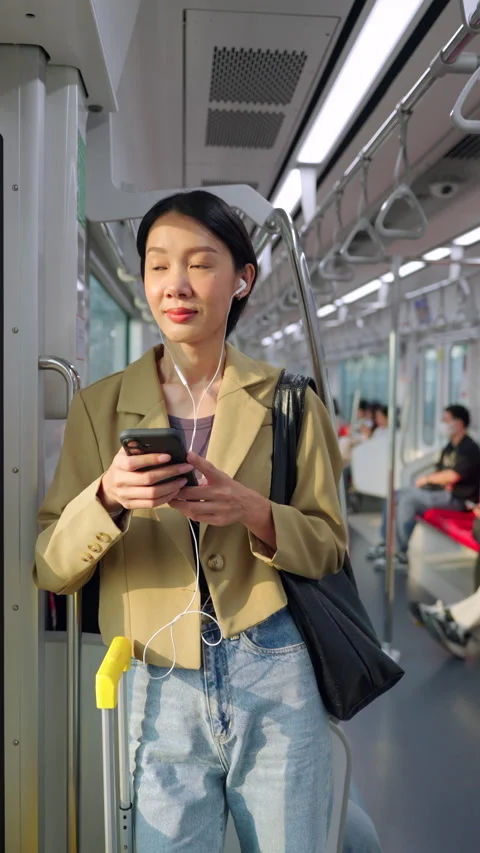 Asian woman using smartphone during morning commute on a city train Stock Footage 345960391