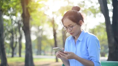 Asian woman using smartphone while sitting on the bench. Stock Footage 83675779