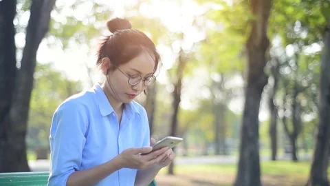Asian woman using smartphone while sitting on the bench. Vídeo Stock 83676338