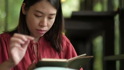 Asian woman using smartphone while reading a book. Stock Footage 134643203