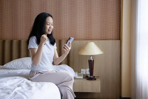 Asian woman using smartphone while relaxing on bed at home. holding smartph.. Stock Photos