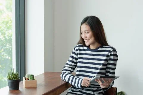 Asian woman using on tablet computer near window at cafe restaurant,Digital a Stock Photos