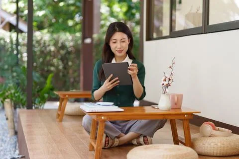 Asian woman using tablet computer sitting floor working from home office mo.. Stock Photos