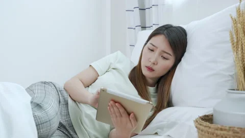 Asian woman using tablet lying down on the bed feeling sleepy and yawning Video stock 151238065