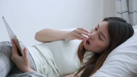 Asian woman using tablet lying down on the bed feeling sleepy and yawning Stock Footage 151238702
