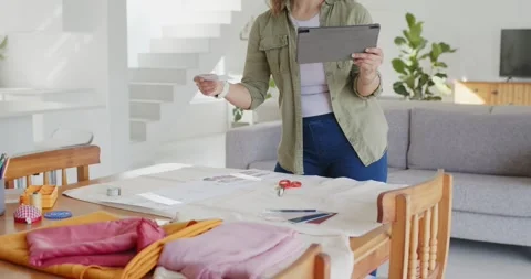 Asian woman using tablet selecting swatch and arranging layout for sewing on Stock Footage 344964630