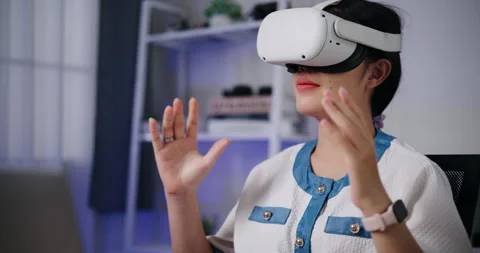Asian woman using a virtual reality headset having fun exploring a 3D virtual  库存影片 293663495