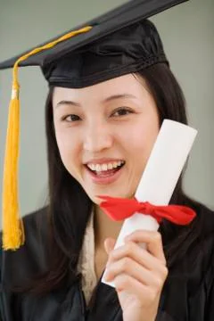 Asian woman wearing graduation cap and holding diploma Stock Photos