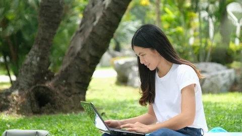 Asian woman work on notebook computer in the park Stock Footage 119909417
