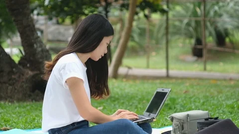 Asian woman work on notebook computer in the park Stock Footage 120073826