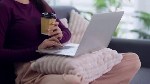 Asian woman working from home using laptop computer holding coffee cup sitt.. 스톡 동영상 334358564